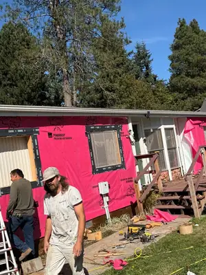 Crew installing pink house wrap around the windows